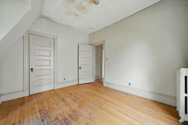 additional living space with hardwood / wood-style flooring, vaulted ceiling, and heating unit