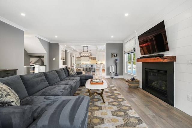 living room with a large fireplace, hardwood / wood-style flooring, and crown molding