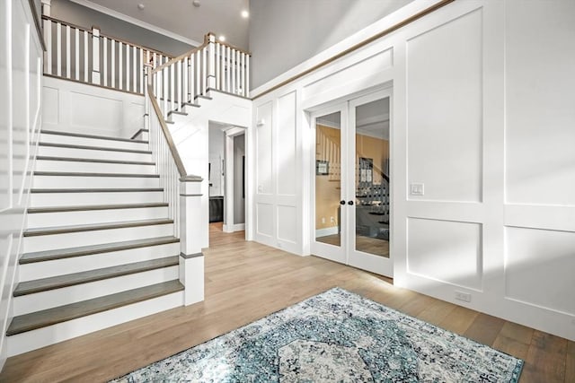 interior space featuring light wood-type flooring, french doors, and a high ceiling