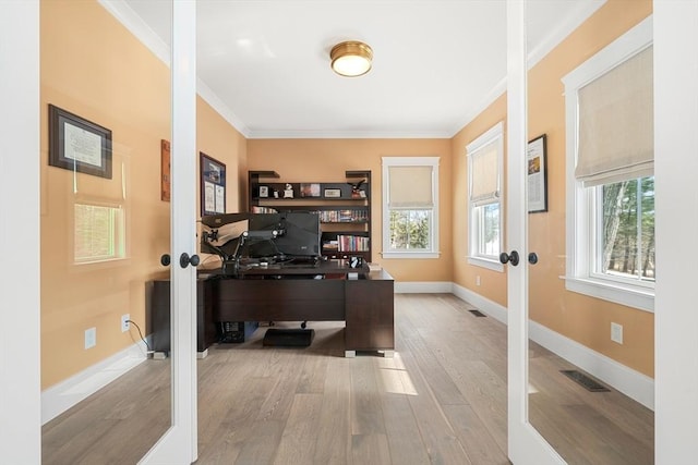 home office with light hardwood / wood-style floors, french doors, and ornamental molding