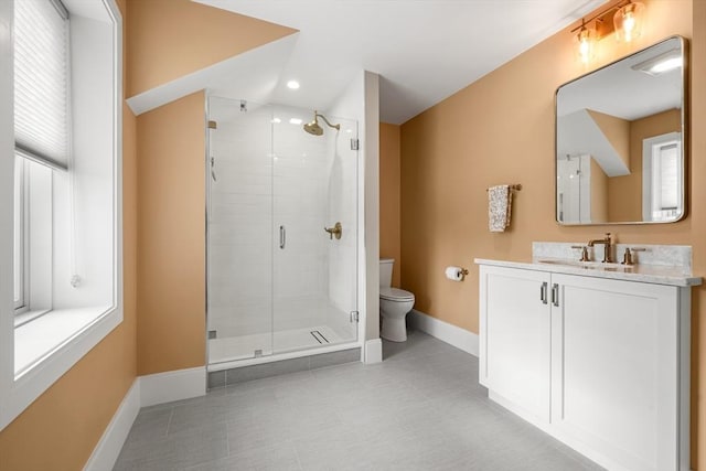 bathroom featuring toilet, vanity, and a shower with door