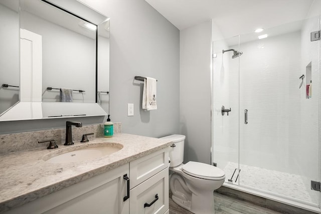 bathroom featuring toilet, wood-type flooring, vanity, and a shower with door