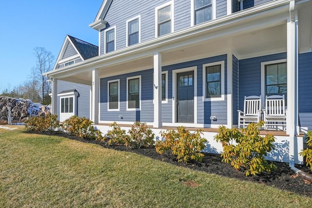 property entrance with covered porch and a lawn