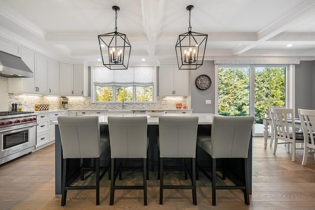 kitchen featuring a breakfast bar area, white cabinetry, a kitchen island, and designer range