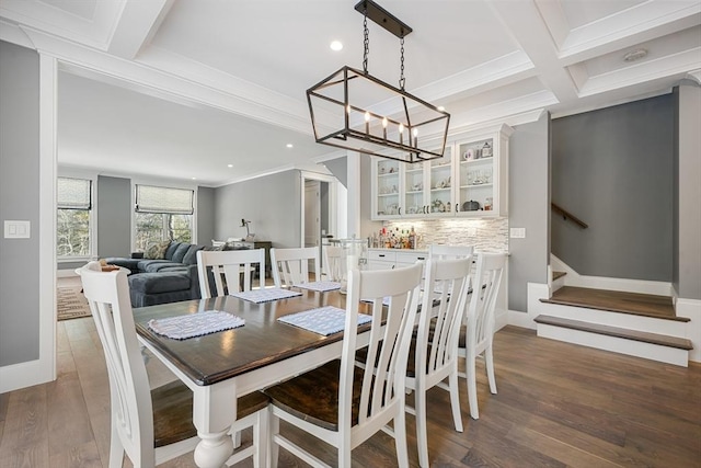 dining area with ornamental molding, coffered ceiling, dark hardwood / wood-style flooring, beamed ceiling, and an inviting chandelier