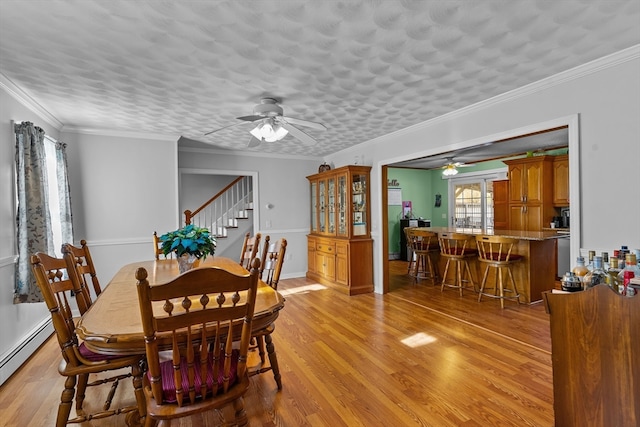 dining space featuring baseboard heating, light hardwood / wood-style flooring, ceiling fan, and ornamental molding