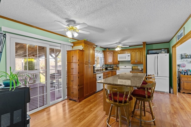 kitchen featuring a kitchen breakfast bar, white appliances, a textured ceiling, and light hardwood / wood-style flooring