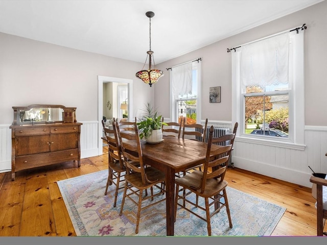 dining space featuring wood-type flooring and wainscoting