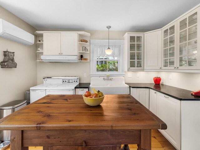 kitchen featuring electric range, open shelves, a sink, a wall mounted air conditioner, and under cabinet range hood