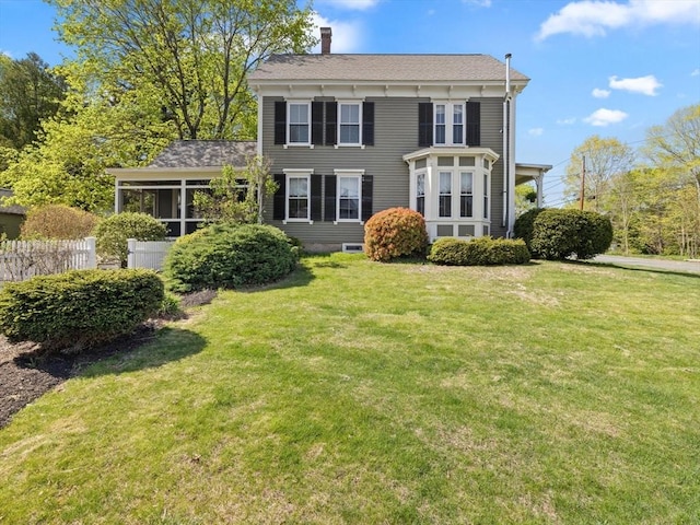 rear view of property with fence, a yard, and a chimney