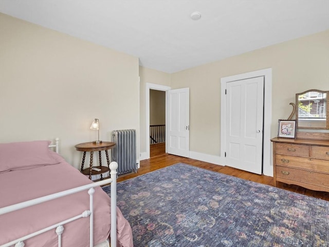 bedroom featuring baseboards, wood finished floors, and radiator