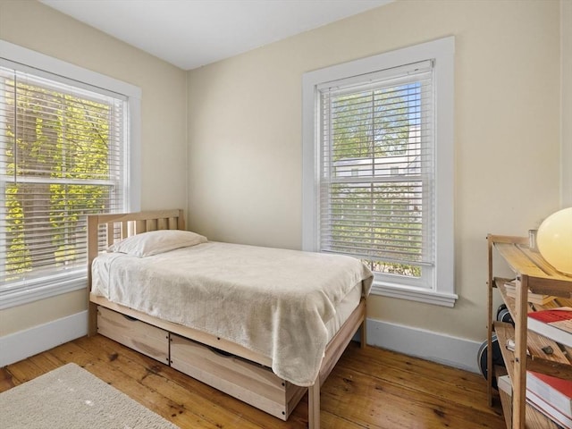bedroom featuring baseboards, hardwood / wood-style floors, and multiple windows
