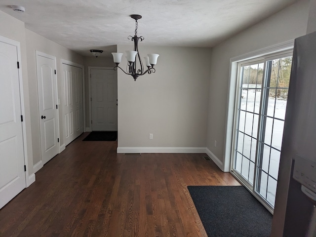 unfurnished dining area with a notable chandelier and dark hardwood / wood-style floors