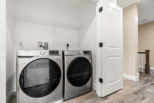 laundry room with laundry area, separate washer and dryer, visible vents, baseboards, and light wood-style floors