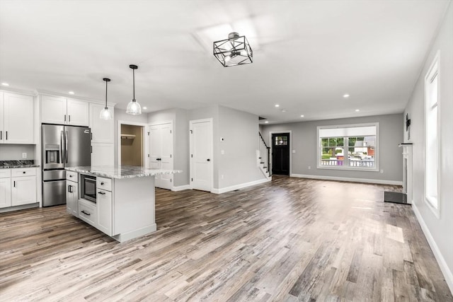 kitchen featuring black microwave, white cabinets, stainless steel refrigerator with ice dispenser, and open floor plan