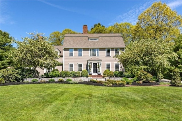 colonial home featuring a chimney and a front lawn