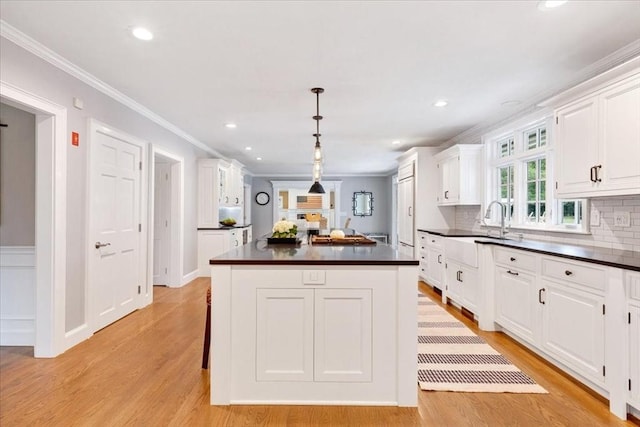 kitchen with a center island, crown molding, white cabinetry, and dark countertops