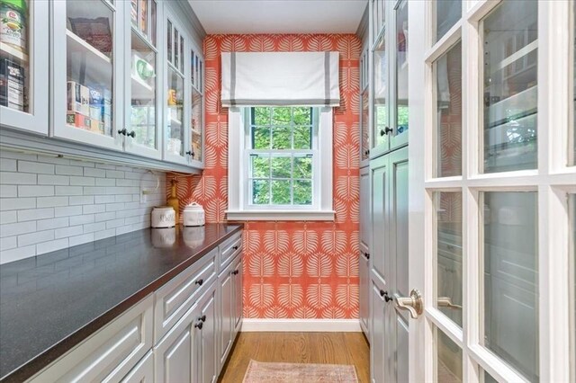 interior space with baseboards, light wood-type flooring, and wallpapered walls