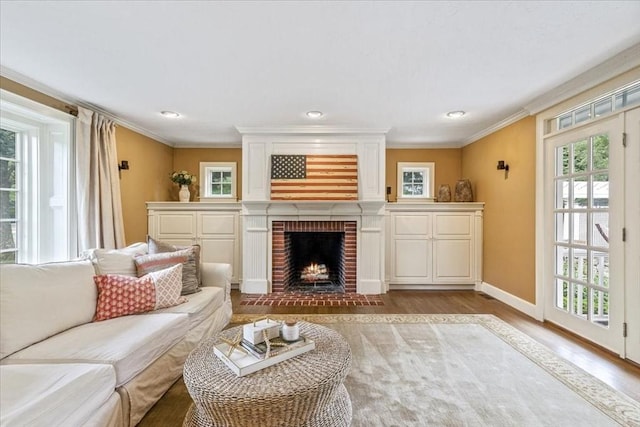 living area featuring light wood-style flooring, a fireplace, ornamental molding, and baseboards