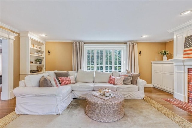 living area with crown molding, light wood-style flooring, recessed lighting, and a brick fireplace