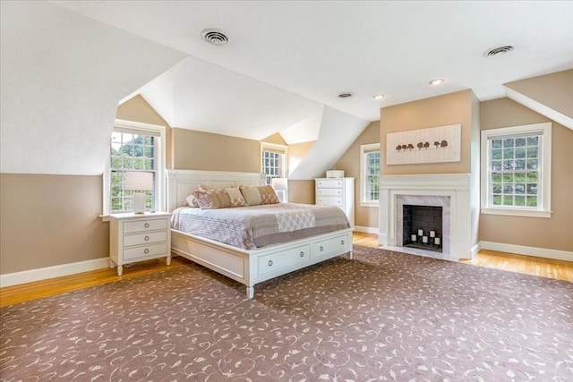 unfurnished bedroom with lofted ceiling, visible vents, baseboards, and wood finished floors