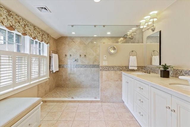 bathroom featuring tile patterned flooring, a walk in shower, visible vents, tile walls, and a sink