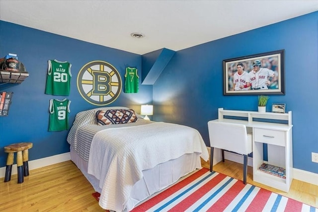 bedroom featuring wood finished floors, baseboards, and visible vents