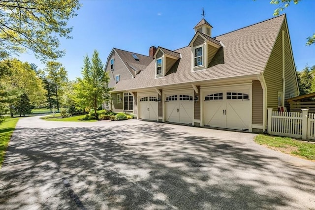 view of home's exterior with aphalt driveway, roof with shingles, fence, and an attached garage