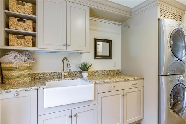 washroom featuring a sink, cabinet space, and stacked washer / dryer