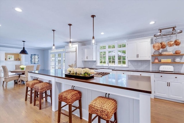 kitchen featuring plenty of natural light, light wood-type flooring, white cabinetry, and dark countertops