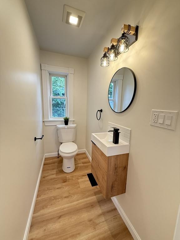 76 Garfield St, Quincy, MA 02169 - half bathroom with wood finished floors, vanity, toilet, and baseboards