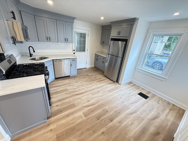 76 Garfield St, Quincy, MA 02169 - kitchen featuring stainless steel appliances, a sink, gray cabinetry, light wood finished floors, and baseboards