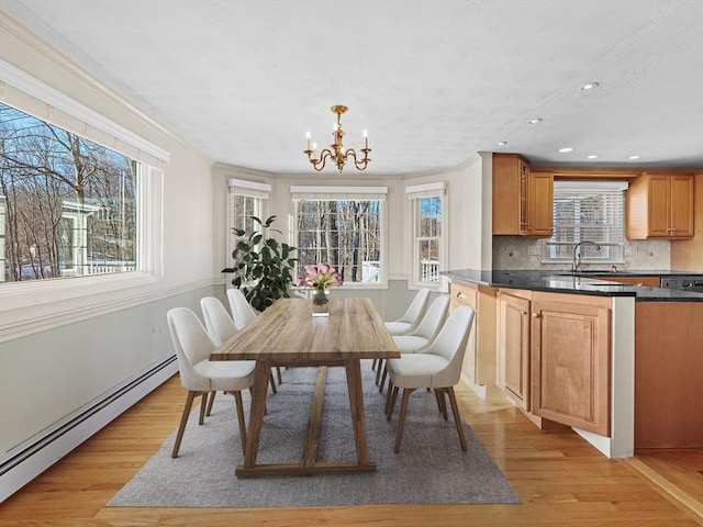 dining space with a baseboard heating unit, ornamental molding, and light wood-type flooring