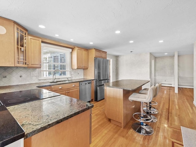 kitchen with appliances with stainless steel finishes, light hardwood / wood-style floors, a kitchen island, and sink