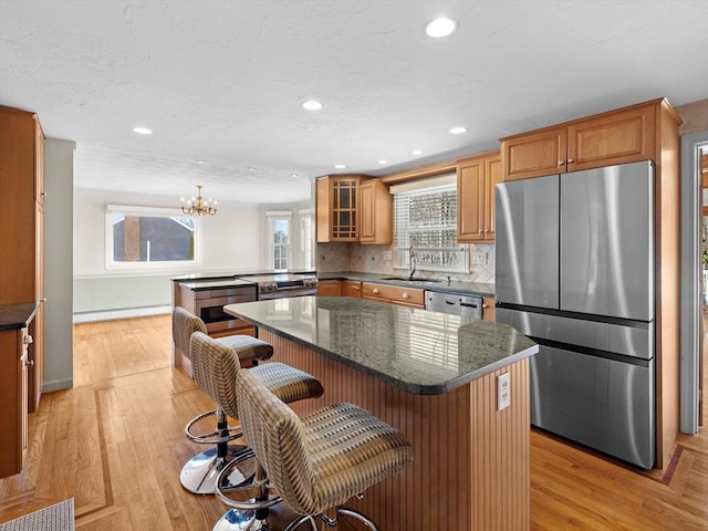 kitchen featuring baseboard heating, appliances with stainless steel finishes, a kitchen island, a kitchen breakfast bar, and kitchen peninsula