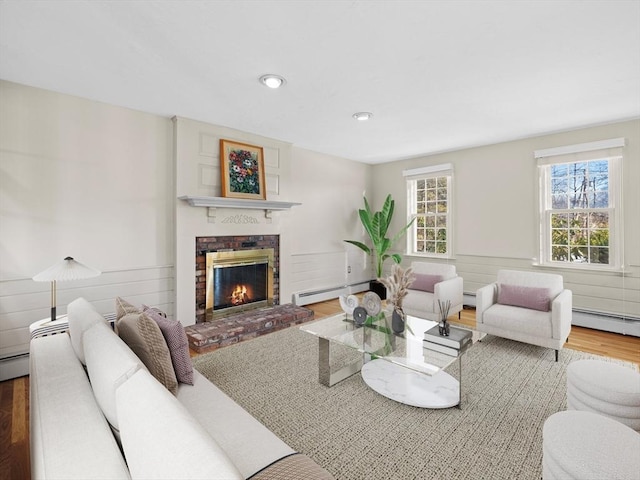 living room featuring hardwood / wood-style floors, a baseboard heating unit, and a fireplace