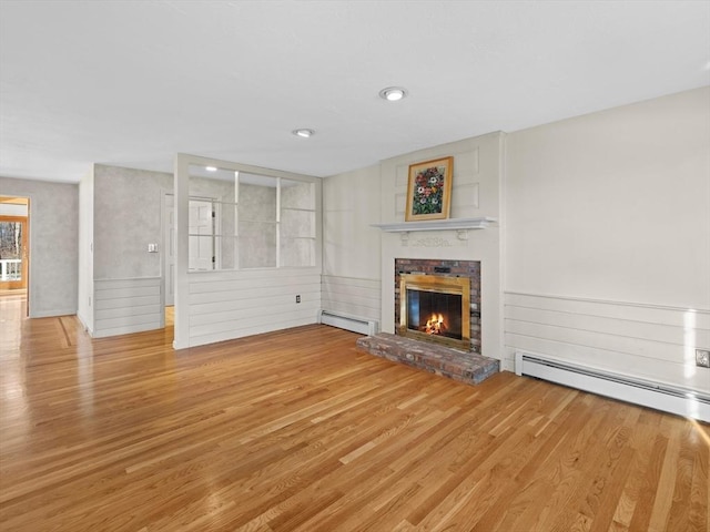 unfurnished living room with a baseboard heating unit, a brick fireplace, and hardwood / wood-style floors