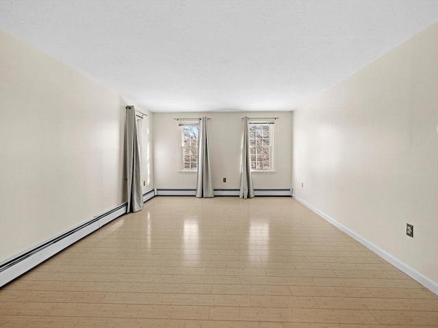 empty room featuring a baseboard heating unit and light hardwood / wood-style floors