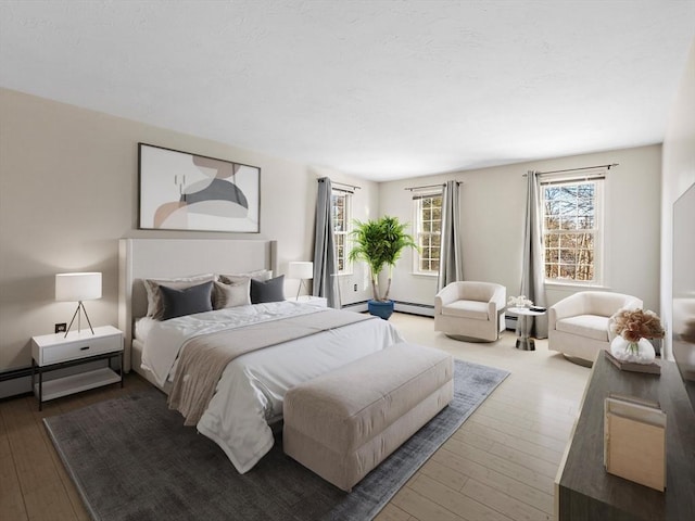 bedroom with a baseboard heating unit and hardwood / wood-style flooring