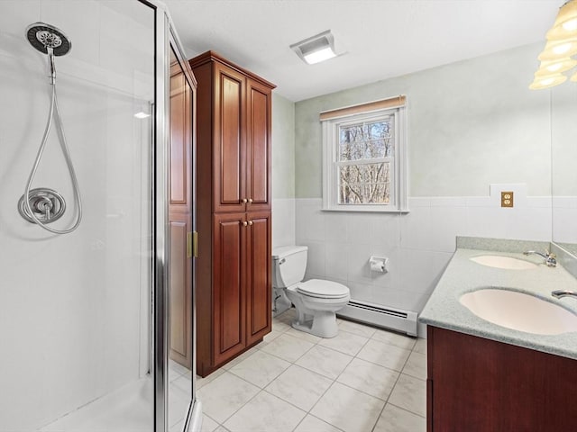 bathroom with a baseboard radiator, tile patterned flooring, vanity, tile walls, and walk in shower