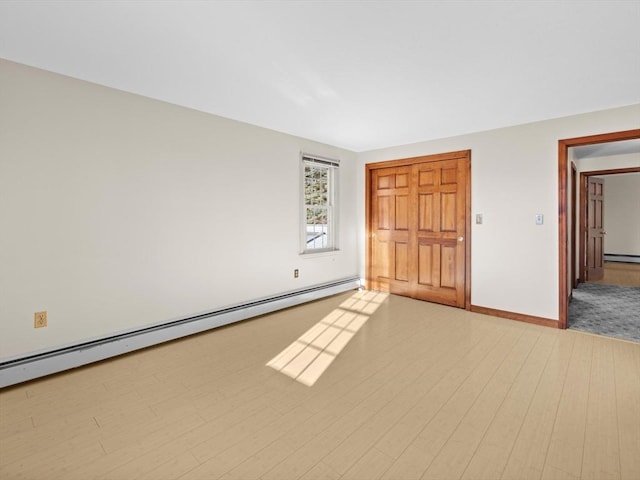 unfurnished bedroom featuring baseboard heating, a closet, and light hardwood / wood-style floors