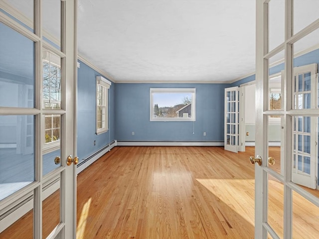 spare room with hardwood / wood-style flooring, a baseboard radiator, crown molding, and french doors