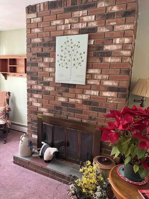 room details with a baseboard radiator, a fireplace, and carpet flooring