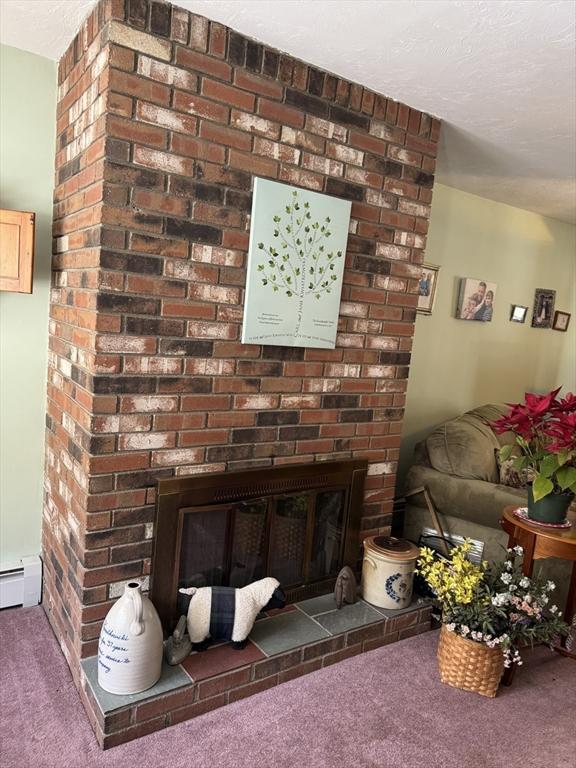 room details featuring carpet floors, a brick fireplace, and a textured ceiling