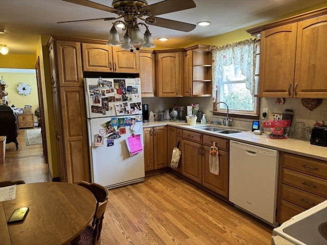 kitchen with light wood finished floors, white appliances, a sink, and decorative backsplash