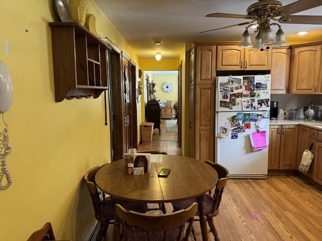 kitchen with tasteful backsplash, brown cabinetry, light wood-style flooring, ceiling fan, and freestanding refrigerator