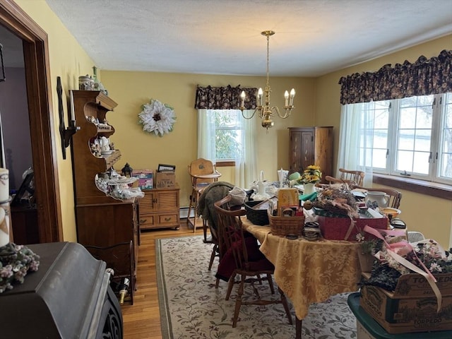 dining area with an inviting chandelier, light wood-style flooring, and baseboard heating