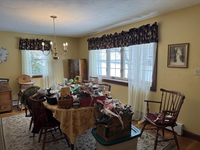 dining room with baseboards, a notable chandelier, baseboard heating, and wood finished floors