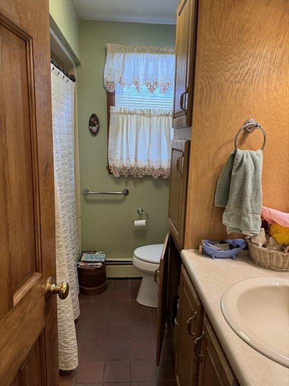 bathroom with a baseboard heating unit, toilet, vanity, and tile patterned floors