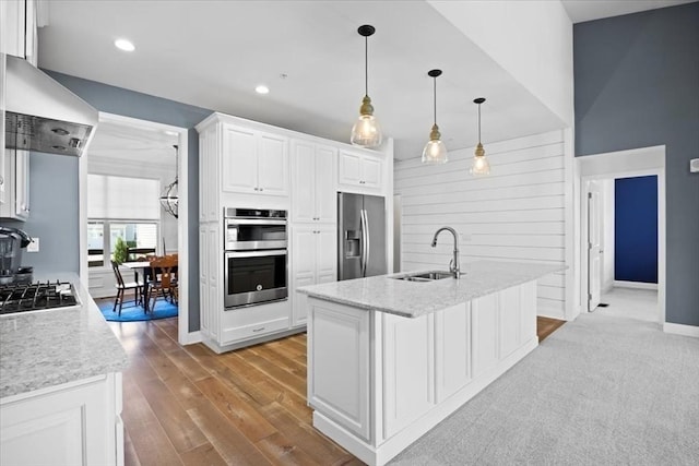 kitchen with white cabinetry, sink, wall chimney exhaust hood, pendant lighting, and appliances with stainless steel finishes